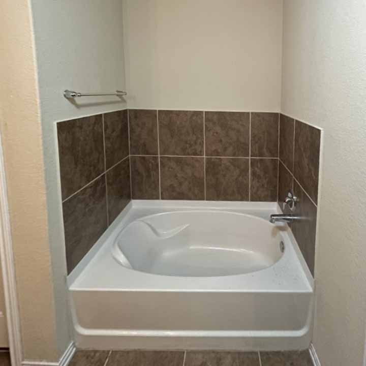 Before - brown tile wall with white tub.